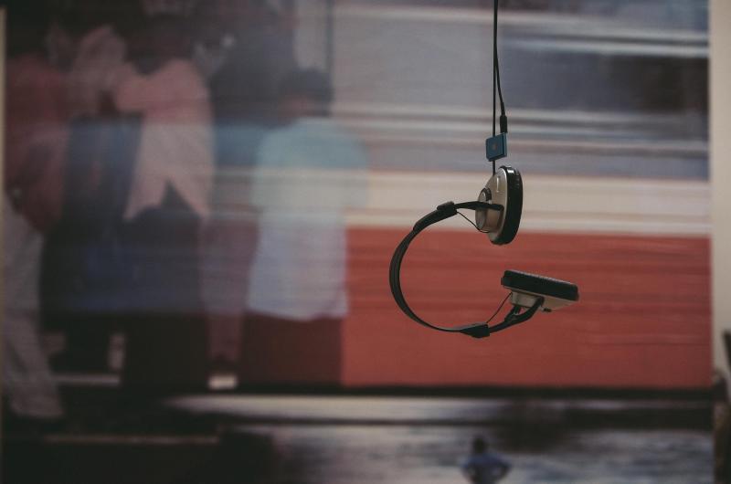 Headphones hanging from a cord in front of a blurred poster 