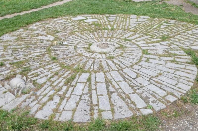 An image of an ammonite laid out in stones in the ground